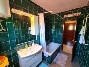 Baño de azulejos verdes con lavabo y bañera en Apartments Angela Rab, en Supetarska Draga 48 fotos más