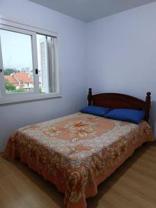 a bed in a bedroom with two windows at Apartamento em Bento Gonçalves-RS in Bento Gonçalves