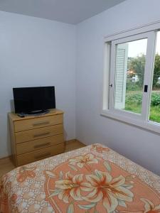 a bedroom with a bed and a dresser and a window at Apartamento em Bento Gonçalves-RS in Bento Gonçalves