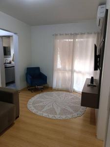 a living room with a blue chair and a rug at Apartamento em Bento Gonçalves-RS in Bento Gonçalves