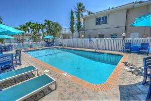 a swimming pool with blue chairs and a white fence at Sea Garden by the Sea in Fort Lauderdale