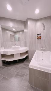 a white bathroom with a sink and a tub at East Dragon Hotel in Taipei