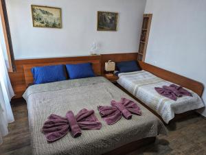 Dos camas con lazos morados en una habitación. en Студио за гости - Лили, en Ognyanovo