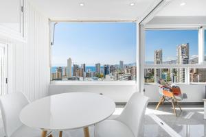 une salle à manger blanche avec vue sur la ville dans l'établissement Gemelos 22-3-21D Apartment Deluxe Levante Beach, à Benidorm