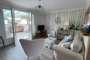 sala de estar con sofá blanco y TV en Maison vue mer Omaha Beach, en Vierville-sur-Mer