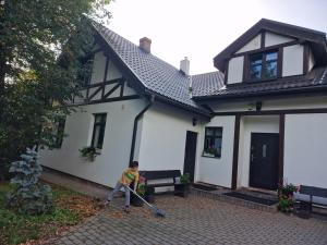 a boy with a broom in front of a house at Valley of Peace with free parking&playground in Ikšķile