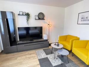 een woonkamer met een televisie en een gele bank bij Black&Yellow Designer Apartment Bielefeld in Bielefeld