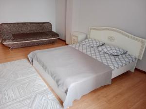 a small bedroom with a bed and a wooden floor at Квартира in Aktobe