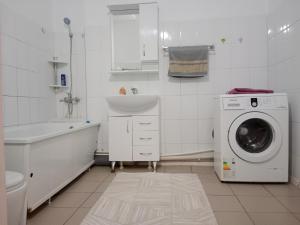 baño blanco con lavadora y lavamanos en Квартира en Aktobe