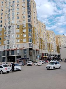 a parking lot with cars parked in front of tall buildings at Квартира in Aktobe