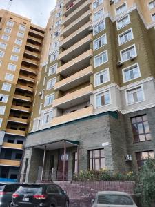 a tall building with cars parked in front of it at Квартира in Aktobe