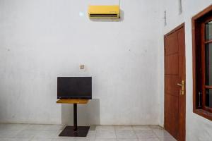a television on a table in a room with a wall at OYO 93161 Nurul Hikmah Homestay Syariah & Sport Center in Sedati