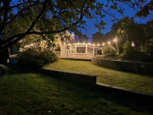 una casa blanca con luces en un patio por la noche en Gap Retreat, en Carrickmore