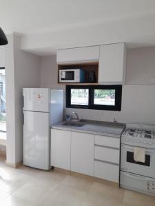 een witte keuken met een koelkast en een wastafel bij Alojamientos Mabel II in Colón