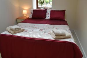 een bed met rode en witte lakens en handdoeken erop bij Ashes Farm - Ingleborough View cottage in Settle