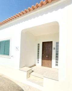 a white house with a wooden door on the side at Casa das Laranjeiras in Vale de Figueira