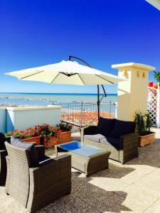 een patio met een parasol, stoelen en een tafel bij Residence Frontemare in Rimini