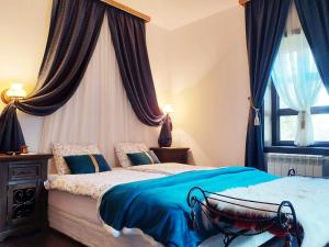 a bedroom with a bed with blue sheets and a window at Golden Horn Guest House in Iskrets