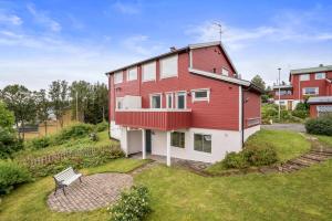 una casa roja y blanca con un banco en un patio en Mountain & Sea View Apartment Tromsø, en Tromsø