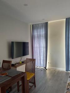 a living room with a dining table and a television at Liana Polo Villas Parklane in Batumi