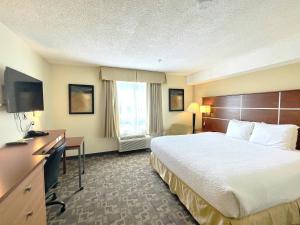 Habitación de hotel con cama, escritorio y TV. en Days Inn by Wyndham Grande Prairie, en Grande Prairie
