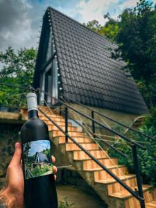 a person holding a bottle of wine in front of a house at N STORY in Keda