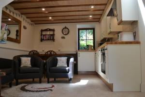 een woonkamer met 2 stoelen en een keuken bij Ashes Farm - Ingleborough View cottage in Settle