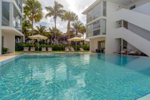uma piscina em frente a um edifício com palmeiras em Beach Haus Key Biscayne Contemporary Apartments em Miami
