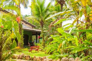 a garden with a red bench in front of a house at Vila dos Tupinambás in Boicucanga