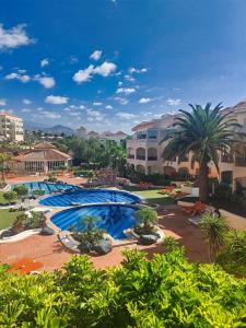 a pool in a resort with palm trees and buildings at Casa Palmu apartment - A peaceful and relaxing oasis in Golf del Sur, Tenerife in San Miguel de Abona