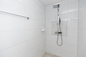 La salle de bains blanche est pourvue d'une douche avec un pommeau de douche. dans l'établissement The Mayfair, à Six Mile Bottom