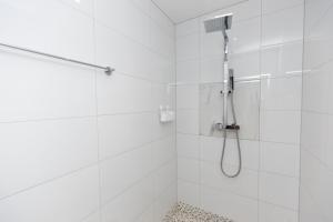 a white bathroom with a shower with a shower head at The Mayfair in Six Mile Bottom