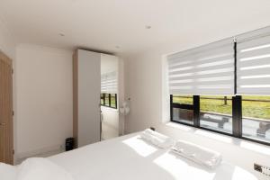 a bedroom with a white bed and a large window at The Mayfair in Six Mile Bottom