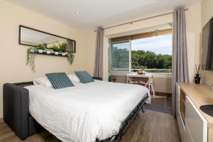 een slaapkamer met een bed en een groot raam bij Le Verd'ô - Piscine - Plage - Parking - Wifi - MyBestLoc in Six-Fours-les-Plages