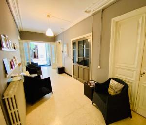 sala de estar con 2 sillas y puerta en Les chambres de la Villa EUGÉNIE, en Lézignan-Corbières