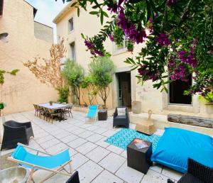 un patio con sillas, una mesa y flores púrpuras en Les chambres de la Villa EUGÉNIE, en Lézignan-Corbières