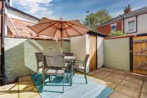 a table and chairs with an umbrella on a patio at Private Yard, Free Parking & Games at Laburnum House in Blackpool