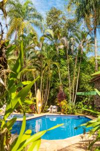 uma piscina num resort com palmeiras em Vila dos Tupinambás em Boiçucanga