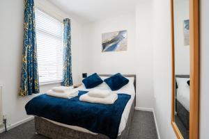 um quarto com uma cama com almofadas azuis e um espelho em Private Yard, Free Parking & Games at Laburnum House em Blackpool