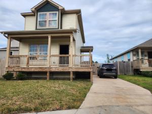 a house with a deck with a car parked in the driveway at 4BR Cruise-Ready Home Walk to Moody Gardens Fenced Yard in Galveston