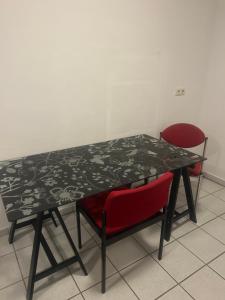 uma mesa com duas cadeiras vermelhas e uma mesa a preto e branco em Ferienwohnung Siegen Eiserfeld 5 em Siegen