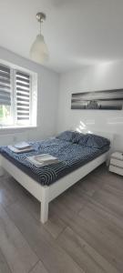 Cama en habitación blanca con marco de cama en Apartament nad jeziorem, en Olsztyn