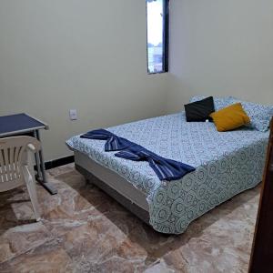 a bed in a room with a table and a chair at Casa nova e ventilada, varanda em Praia de Jacaraípe ES in Serra