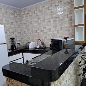 eine Küche mit einer schwarzen Arbeitsplatte und einer Mikrowelle in der Unterkunft Casa nova e ventilada, varanda em Praia de Jacaraípe ES in Serra