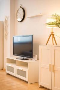 Estudio con vistas y parking في مالقة: تلفزيون على خزانة بيضاء في غرفة مع ساعة