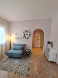 ein Wohnzimmer mit einem blauen Sofa und einer Uhr an der Wand in der Unterkunft Il Nido Casa indipendente a Fiumicino Self check in in Fiumicino