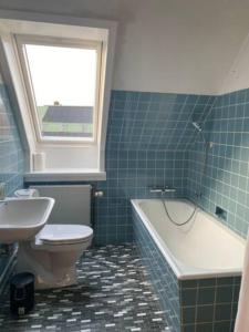 a bathroom with a toilet and a tub and a sink at Apartment near nature in Birkerød