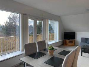 salon ze stołem, krzesłami i oknami w obiekcie Apartment near nature w mieście Birkerød