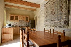 eine Küche mit einem Holztisch und einem großen Teppich an der Wand in der Unterkunft Mill House in Għarb