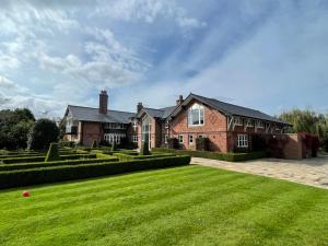 a large brick house with a large grass yard at Fernside house and barns in Pickmere
